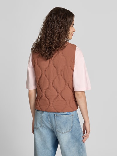 Frauenmodel trägt Steppweste mit Stehkragen und Label-Stitching von Superdry in Braun, sichtbare Knopfleiste, Jeans und T-Shirt, Ganzkörperansicht Rückansicht, Slim Fit, Rückenlänge 53 cm, Schulterbreite 34 cm, Brustweite 36 cm.
