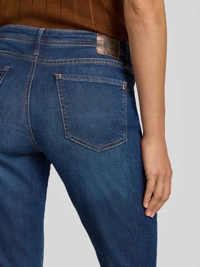 Kobieta nosi Bootcut-Jeans aus Baumwoll-Mix Modell 'SHAKIRA' od Brax, niebieski denim, widok z tyłu, kontekst: damskie jeansy bootcut od Brax, zbliżenie tylnej części.