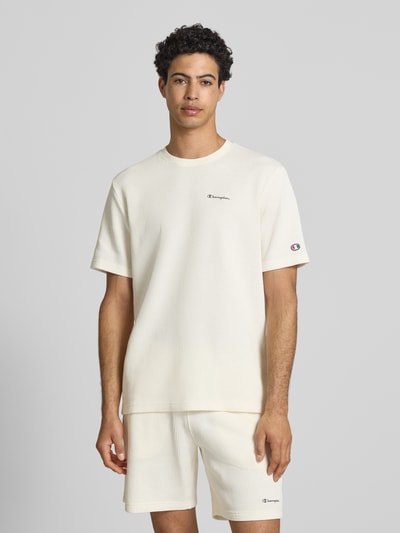 Männermodel trägt T-Shirt mit Strukturmuster und Label-Stitchings von CHAMPION in Creme, Baumwoll-Mix, Regular-Fit, Ganzkörperansicht von vorne. Herren T-Shirt, Rückenlänge bei Größe M: 68 cm.