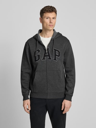 Männermodel trägt Sweatjacke mit Logo und Känguru-Tasche von GAP aus Baumwoll-Mix, Regular-Fit, Anthrazit, Ganzkörperansicht von vorne.