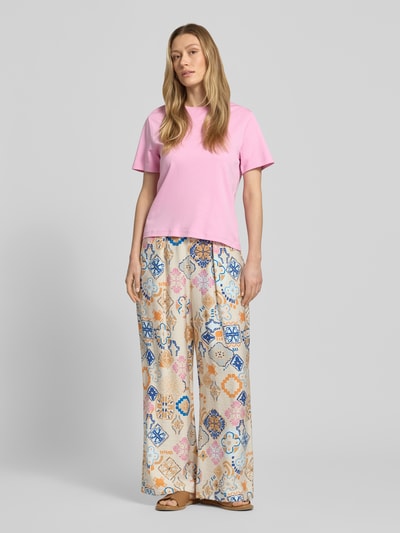 Frauenmodel trägt Wide Fit Stoffhose aus Viskose-Mix Modell 'Lancie' von ICHI mit floralem Print, sanfte Farben, Ganzkörperansicht von vorne.