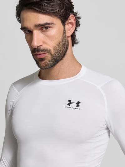 Mannelijk model draagt Slim Fit Longsleeve met Logo-Print van Under Armour, wit, ronde hals, elastische stof, slim fit, logo voor, close-up bovenlichaam