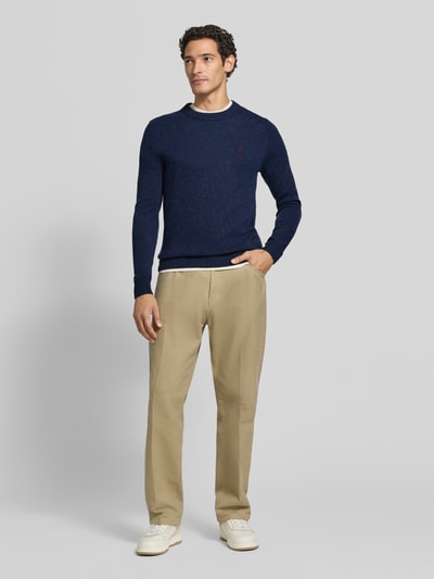 Männermodel trägt Slim Fit Strickpullover aus reiner Wolle mit Label-Stitching von MCNEAL, gerippte Abschlüsse, Ganzkörperansicht von vorne.