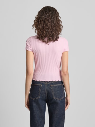 Modelka nosi Slim Fit T-Shirt mit Viskose-Anteil Modell 'EMMA' od Only w jasnoróżowym kolorze, struktura prążkowana, widok całej sylwetki z tyłu.