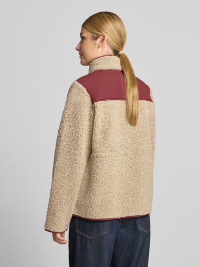 Frauenmodel trägt Fleecejacke mit Zweiwege-Reißverschluss Modell 'Elisa Eli' von MOS MOSH, beige mit bordeauxfarbenen Details, strukturierte Oberfläche, Ganzkörperansicht Rückansicht, Damen Fleecejacke Regular Fit, Stehkragen, Eingrifftaschen, Rückenlänge 58 cm, Schulterbreite 41 cm, Brustweite 48 cm, Ärmellänge 63 cm.