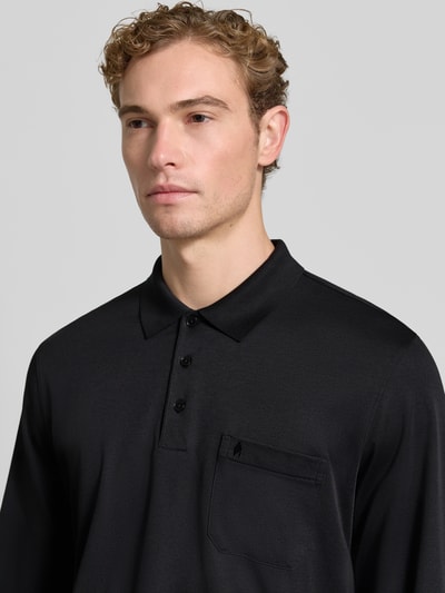 Männermodel trägt Regular Fit Poloshirt aus Baumwoll-Mix von RAGMAN in Schwarz mit Brusttasche, Nahaufnahme Oberkörper.