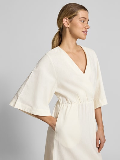 Frauenmodel trägt Midikleid aus Leinen-Mix mit Kimonoärmeln Modell 'Laura' von GUIDO MARIA KRETSCHMER WOMAN, V-Ausschnitt, Wickel-Optik, taillierter Schnitt, cremefarben, weiche Textur, Nahaufnahme Oberkörper.