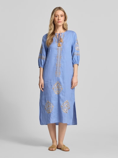 Frauenmodel trägt Tunikakleid aus Leinen mit Tunikakragen und Quasten von Emily Van den Bergh in Blau mit Stickereien, Midikleid, Loose Fit, Ganzkörperansicht von vorne.
