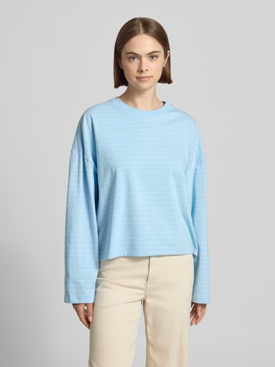 Frauenmodel trägt Longsleeve mit Rundhalsausschnitt von OH APRIL in Hellblau, lockerer Schnitt, reine Baumwolle, Ganzkörperansicht von vorne.