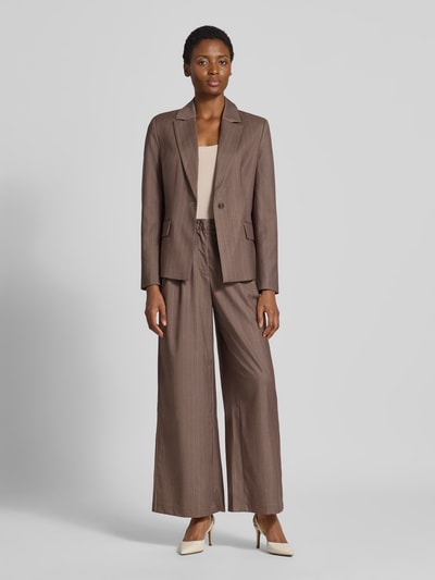 Kobiece modelka nosi żakiet Slim Fit Blazer mit Pattentaschen Model 'Fee' od GUIDO MARIA KRETSCHMER WOMAN, Mieszanka materiałów z dodatkiem wiskozy, kołnierz z połami, kieszenie z patką, długość tyłu w rozmiarze 36: 64 cm, szerokość w rozmiarze 36: 44 cm, długość rękawów w rozmiarze 36: 64 cm, brązowy kolor, proste faktury, prostokątne kształty. Ganzkörperansicht z przodu.