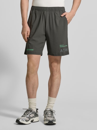 Männermodel trägt Shorts mit elastischem Bund Modell 'HALO AIR' von HALO in Dunkelgrau, Regular-Fit, Material-Mix mit Stretch-Anteil, Bundweite 40 cm, Innenbeinlänge 21 cm, Produkt-Kontext sichtbar, Ganzkörperansicht von vorne.