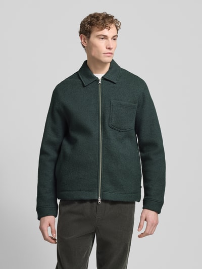 Männermodel trägt Hemdjacke mit Reißverschluss Modell 'HANNES' von Samsøe Samsøe aus reine Wolle, Regular-Fit, Brusttasche, Ganzkörperansicht von vorne.