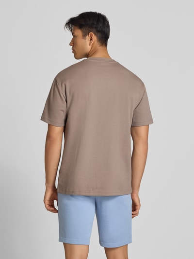 Männermodel trägt Relaxed Fit T-Shirt aus reiner Baumwolle Modell 'ESS ELEVATED' von PUMA, Herren T-Shirt, hellbraun, Ganzkörperansicht Rückansicht.