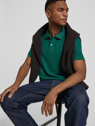 Männermodel trägt Regular Fit Poloshirt mit Logo-Stitching von Fynch-Hatton in Grün, reine Baumwolle, kurze Ärmel, Nahaufnahme Oberkörper.