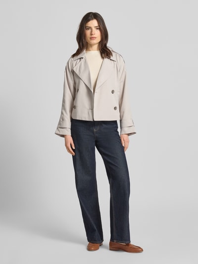 Frauenmodel trägt Regular Fit Trenchcoat mit Schulterriegeln von Tom Tailor Denim, efekt: jednolity kolor, krój regular fit, kołnierz z połami, listwa guzikowa, detale z guzikami, długi rękaw z regulacją na patkę, wpuszczane kieszenie, wykończenie materiału: splot twill, Ganzkörperansicht von vorne