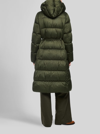 Frauenmodel trägt Steppmantel mit Bindegürtel von Marc Cain in Dunkelgrün, glänzende Textur, regelmäßige Steppung, Ganzkörperansicht Rückansicht. Damen Steppmantel, Regular Fit, Kapuze, verdeckter Reißverschluss, Eingrifftaschen, Bindegürtel, Rückenlänge 107 cm, Schulterbreite 43 cm, Brustweite 58 cm, Ärmellänge 63 cm.