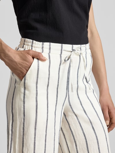 Frauenmodel trägt Straight Fit Leinenhose aus reinen Leinen Modell 'Callie' von MAC, weiß mit schwarzen Streifen, Nahaufnahme Oberkörper, verkürzte Passform, elastischer Bund mit Tunnelzug, reine Leinen-Textur.