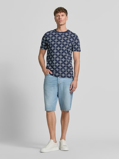 Mannenmodel draagt Regular Fit T-shirt uit puur katoen van s.Oliver RED LABEL, donkerblauw met wit patroon, lichtblauwe short, witte sneakers, volledige vooraanzicht.