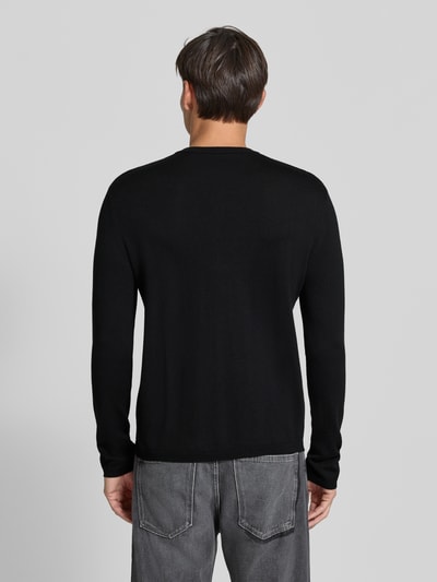Männermodel trägt schwarzen Strickpullover mit Henley-Kragen von DRYKORN aus reiner Baumwolle, gerader Schnitt, gerippte Abschlüsse, Ganzkörperansicht Rückansicht.