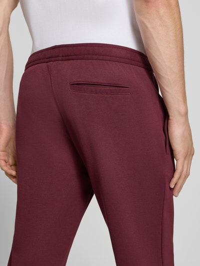Männermodel trägt Straight Fit Hose mit Baumwoll-Anteil Modell 'Parker' von MCNEAL in Dunkelrot, Material-Mix, Detailaufnahme Rückansicht.
