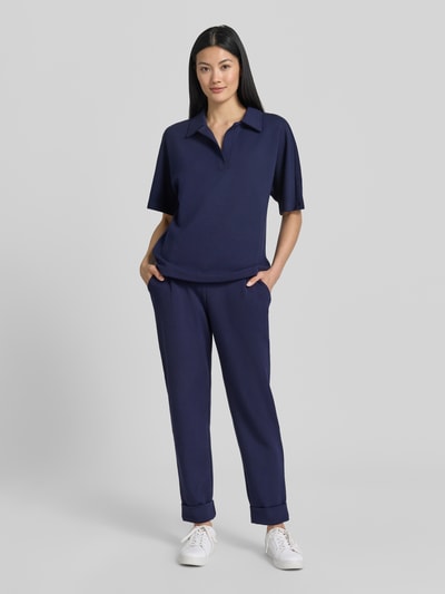 Frauenmodel trägt Straight Fit Sweatpants in verkürzter Passform von Christian Berg Woman in Dunkelblau, Baumwoll-Modal-Anteil, Bundfalten, Ganzkörperansicht von vorne.