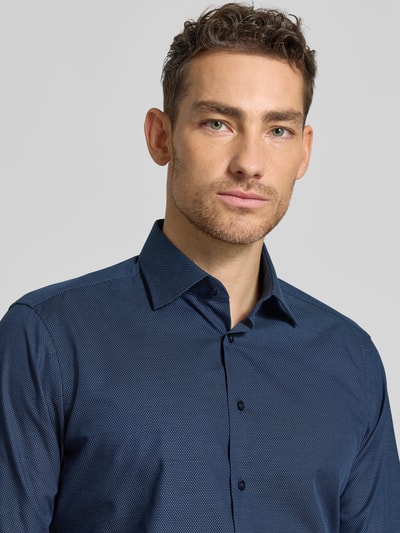 Męski model nosi Regular Fit Business-Hemd aus Baumwolle mit Kentkragen von Christian Berg Men, kolor granatowy z drobnym wzorem, krój regular fit, bawełna, kołnierzyk typu kent, listwa guzikowa, długość tyłu w rozmiarze 39/40 77 cm, szerokość w rozmiarze 39/40 43 cm, długość rękawów w rozmiarze 39/40 67 cm, zbliżenie na górną część torsu