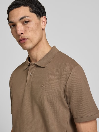 Męski model nosi Regular Fit koszulkę polo z fakturowanym wzorem model 'AUSTIN' od Jack & Jones z mieszanki bawełny, haft, listwa guzikowa, długość tyłu w rozmiarze M: 69 cm, kolor jasnobrązowy, fakturowana powierzchnia, półzbliżenie górnej części ciała.