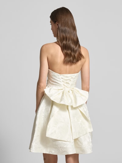 Frauenmodel trägt Minikleid mit floralem Allover-Stitching von Hey Kyla in Creme, Zierschleife, abnehmbare Träger, Tailliert, Rückenlänge 85 cm, Brustweite 34 cm, Ganzkörperansicht Rückansicht.