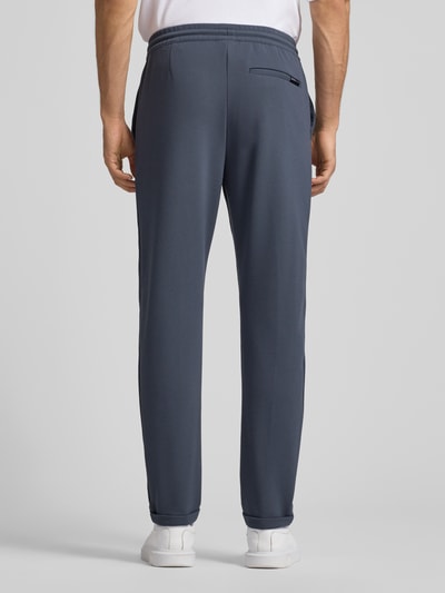 Männermodel trägt Tapered Chino mit Viskose-Anteil von Tom Tailor Denim in Optik: Unifarben, sichtbare Gesäßtaschen, fixierter Umschlag, Ganzkörperansicht Rückansicht.