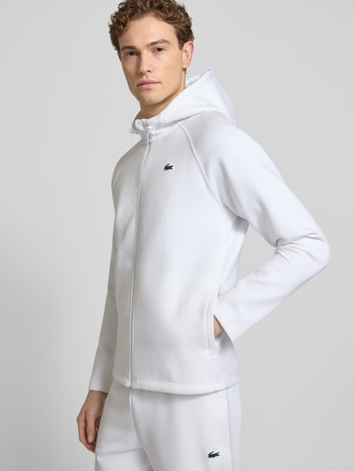 Männermodel trägt Regular Fit Sweatjacke mit Baumwoll-Anteil von Lacoste Sport, weiß, unifarben, Kapuze, Logo-Patch, Ganzkörperansicht von vorne