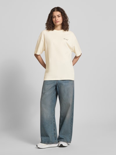 Frauenmodel trägt T-Shirt im Oversize-Fit mit Blumen-Backprint von REVIEW aus Reine Baumwolle, Rundhalsausschnitt, Halbarm, Ganzkörperansicht von vorne.