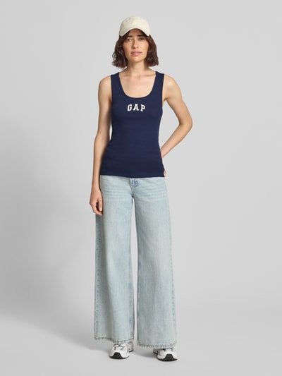 Frauenmodel trägt Tanktop mit Logo-Print und Rundhalsausschnitt von GAP in Dunkelblau, körpernah, fein gerippt, Baumwoll-Mix mit Stretch, Ganzkörperansicht von vorne.