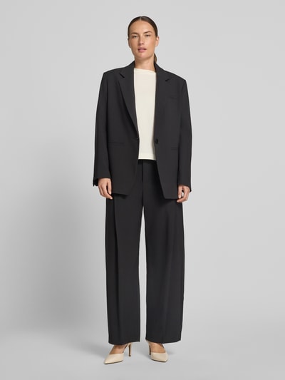 Vrouwenmodel draagt Barrel Fit broek met achterzakken model 'UNPACK' van DRYKORN in zwart, materiaalmix met viscose, damesbroek; volledig lichaamsbeeld van voren. Context: bandwijdte maat 27/32: 39 cm, binnenbeenlengte: 75 cm.