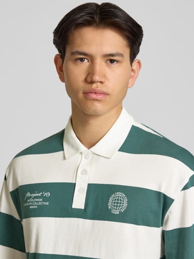 Mężczyzna nosi Relaxed Fit Poloshirt aus reiner Baumwolle Modell 'DEVIN' od Only & Sons, zielono-białe szerokie pasy, nadruk, krótki rękaw, jersey, półzbliżenie górnej części ciała.