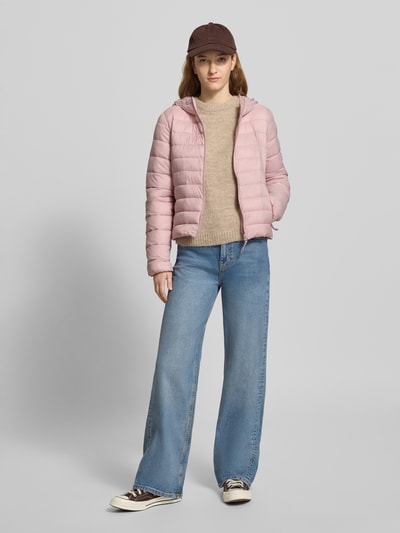 Modelka nosi Kurtka pikowana Regular Fit Steppjacke mit Kapuze Modell 'TAHIA' von ONLY, efekt: jednolity kolor, krój regular fit, kaptur z tunelem, zamek błyskawiczny, długi rękaw, elastyczne zakończenia rękawów, boczne wpuszczane kieszenie, jasnoróżowa, gładka tekstura, widok całej sylwetki z przodu.