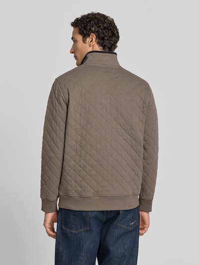 Männermodel trägt Regular Fit Troyer aus Baumwoll-Mix von GANT in Braun mit Stehkragen, Strukturmuster, gerippten Abschlüssen, Ganzkörperansicht Rückansicht.