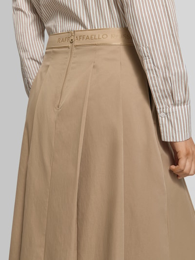 Männermodel trägt spódnica midi z wszytym zamkiem błyskawicznym oraz wyhaftowanym logo model 'Vivian' od Raffaello Rossi, szerokość w rozmiarze 36: 38 cm, całkowita długość w rozmiarze 36: 81 cm, beżowy kolor, widoczne plisy, detailaufnahme tyłu.