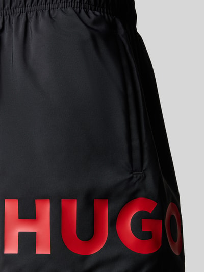 Produktfoto, Badeshorts mit Label Print Modell 'MAKAI' von HUGO in Schwarz mit rotem Schriftzug, glatte Popeline, elastischer Bund, seitliche Eingrifftasche