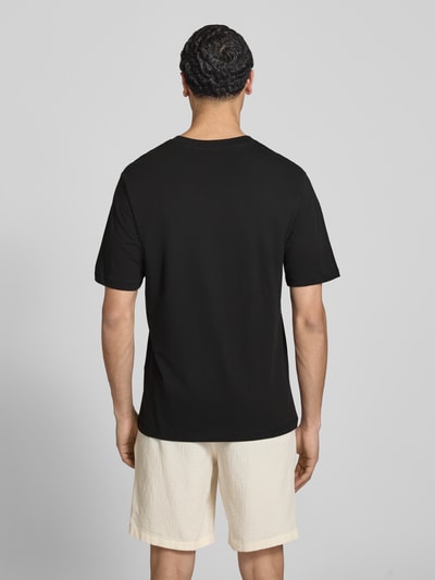 Męski model nosi T-Shirt mit Logo und Rundhalsausschnitt od Jack & Jones, czarny, czysta bawełna, krój regular fit, długość tyłu w rozmiarze M: 71 cm, widok całej sylwetki z tyłu.