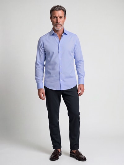 Männermodel trägt Slim Fit Business Hemd mit Kentkragen aus Feintwill von Seidensticker in Hellblau, feine Webstruktur, Ganzkörperansicht von vorne.