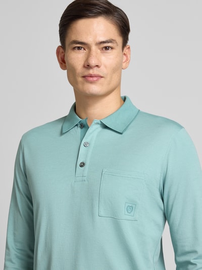 Männermodel trägt Poloshirt mit Brusttasche von Lerros aus Baumwoll-Mix in Türkis, Regular-Fit, Label-Detail, Nahaufnahme Oberkörper.