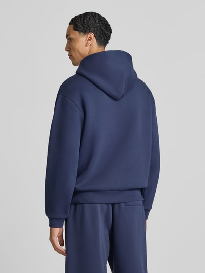 Männermodel trägt Sweatjacke aus Baumwoll-Mix von REVIEW in Dunkelblau, lockere Passform, weiche Textur, Ganzkörperansicht Rückansicht.
