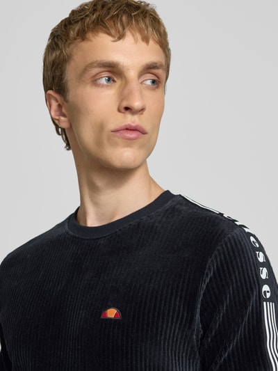 Männermodel trägt Herren T-Shirt mit Logo Modell 'MADORI' von Ellesse aus schwarzem Baumwoll-Mix mit Stretch-Anteil, Nahaufnahme Oberkörper.