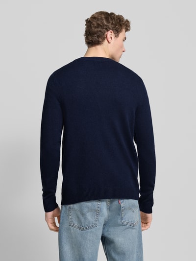 Männermodel trägt Strickpullover aus Lammwolle Modell 'Tay' von Wood Wood in Dunkelblau, Regular-Fit, Rückenansicht, feine Textur.