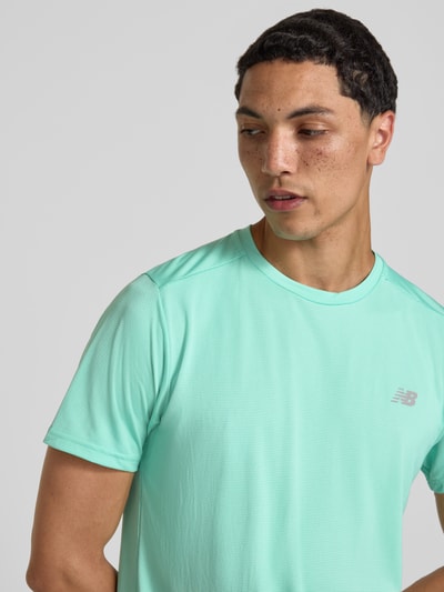 Männermodel trägt Funktionsshirt mit Rundhalsausschnitt und Logo von New Balance in Mint, glatte Textur, Regular-Fit, Nahaufnahme Oberkörper