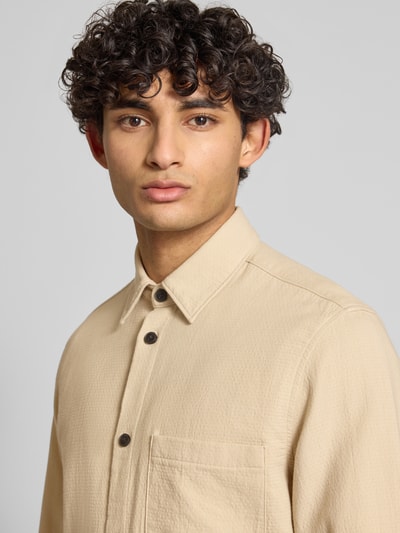 Männermodel trägt Regular Fit Freizeithemd aus reiner Baumwolle von Marc O'Polo Denim in Beige, strukturierte Webware, Nahaufnahme Oberkörper.