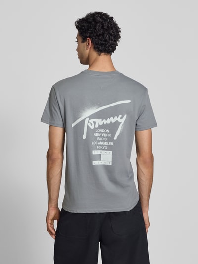 Männermodel trägt Regular Fit T-Shirt aus reiner Baumwolle von Tommy Jeans, Optik: Unifarben, Label-Schriftzug, Ganzkörperansicht Rückansicht.