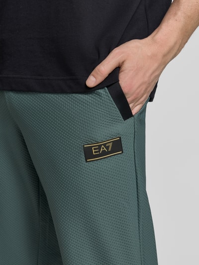 Männermodel trägt Regular Fit Sweatpants mit Strukturmuster von EA7 Emporio Armani, Elastischer-Material-Mix, Eingrifftaschen, Nahaufnahme Oberkörper.
