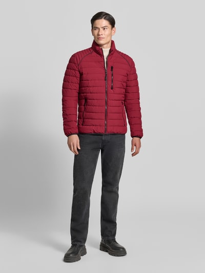 Mannenmodel draagt Steppjacke mit Stehkragen und Reißverschlusstaschen van LERROS in rood met zwarte details, regular fit, ganzlichaamsaanzicht van voren. Ruglengte maat M 69 cm, schouderbreedte 46 cm, borstwijdte 60 cm, mouwlengte 69 cm.