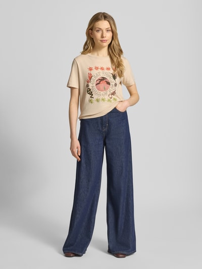 Frauenmodel trägt Regular Fit T-Shirt mit floralem Stitching von Scotch & Soda, Damen T-Shirt aus reiner Baumwolle, Motiv-Print, Rundhalsausschnitt, Rückenlänge in Größe S 55 cm, warme Farben, glatte Textur, Ganzkörperansicht von vorne.